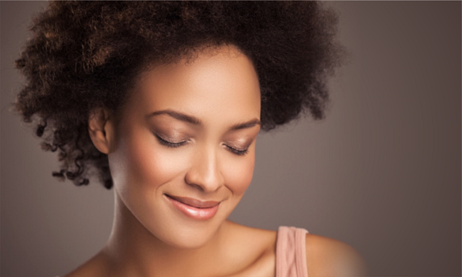 Woman with kinky natural hair eyes closed smiling