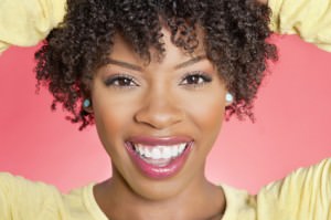 Close-up portrait of an African American woman smiling over colored background