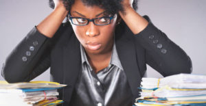 Stressed black woman with a pile of papers on desk