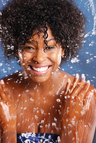 Black woman with wet natural hair splashing water