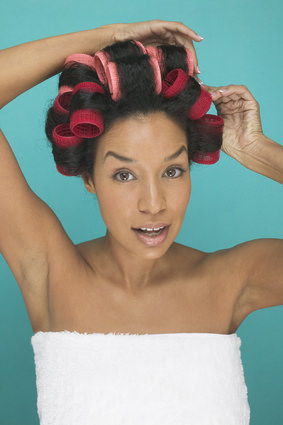 African American woman in towel putting rollers in her natural hair
