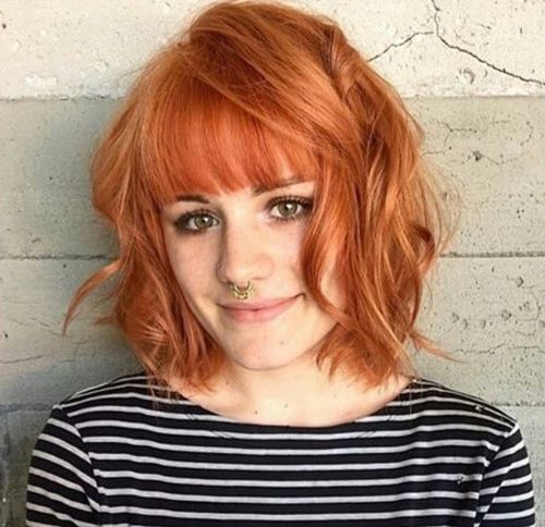 messy curly bob hairstyle with straight bangs