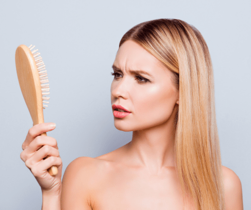 Woman looking at hair brush.