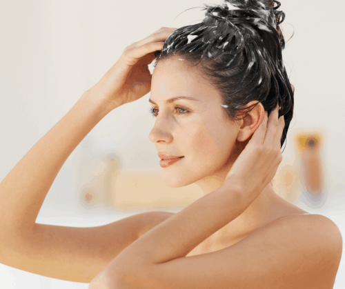 Woman conditioning hair and massaging scalp to stimulate hair growth.
