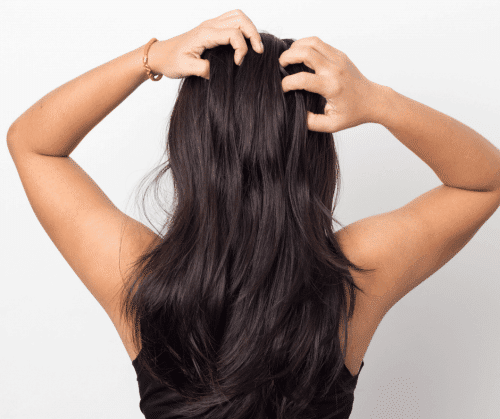 Woman with long, healthy hair massaging her scalp.