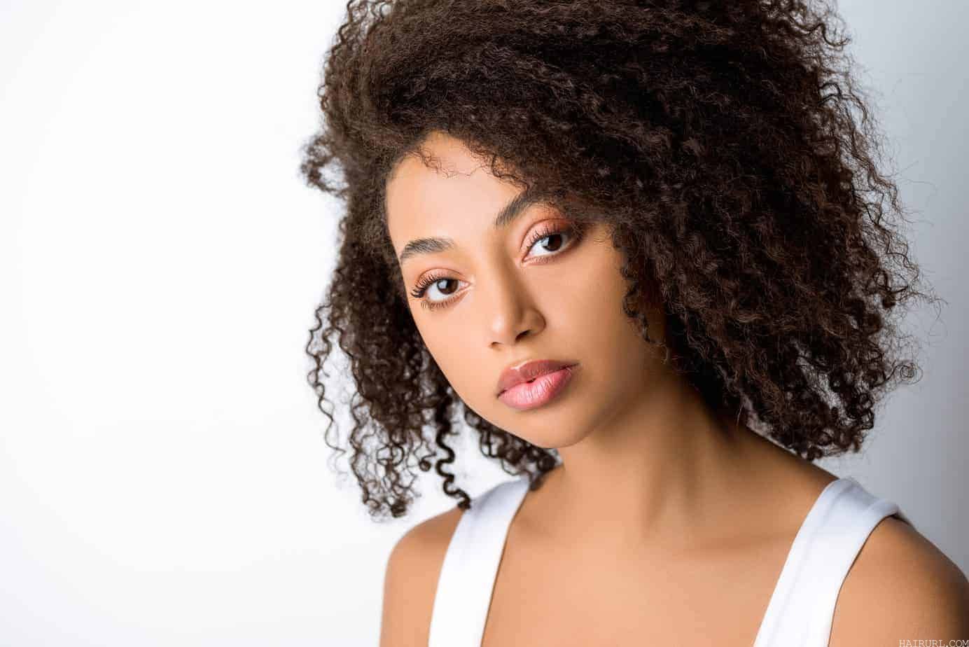 mixed race female looking directly into the camera wearing red lipstick, eye shadow and a white tank top