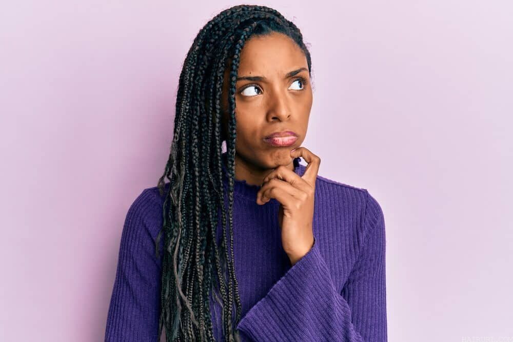 Black girl looking confused while wearing braid extensions with synthetic hair