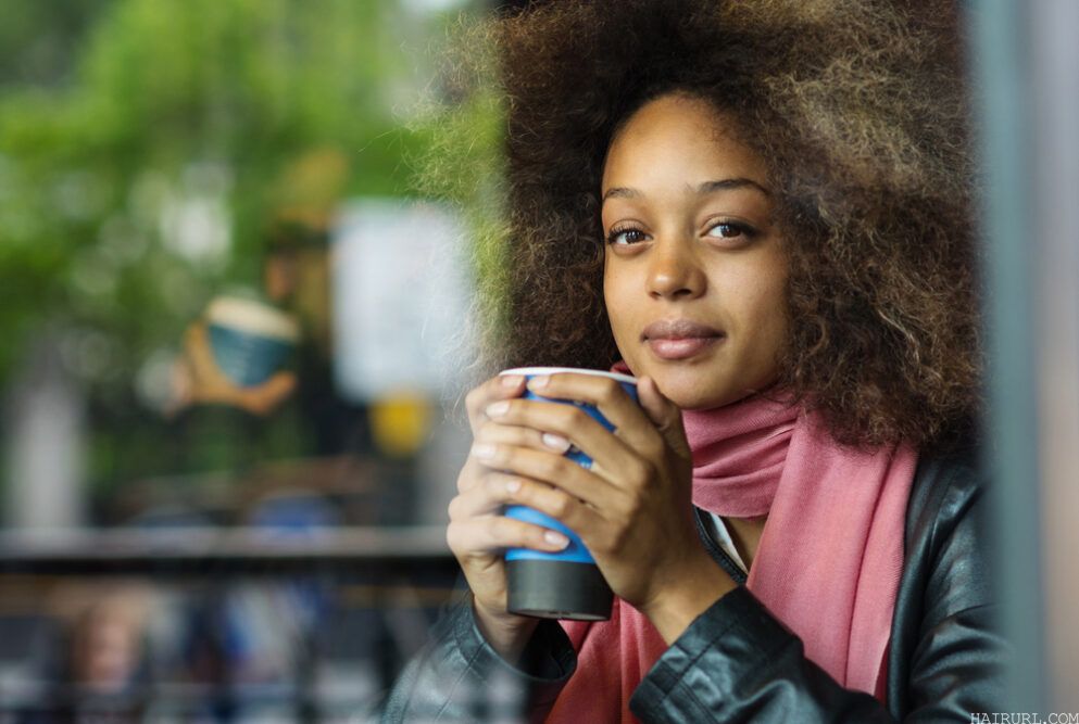 Cute black girl with dark brown hair dyed with black henna drinking coffee.
