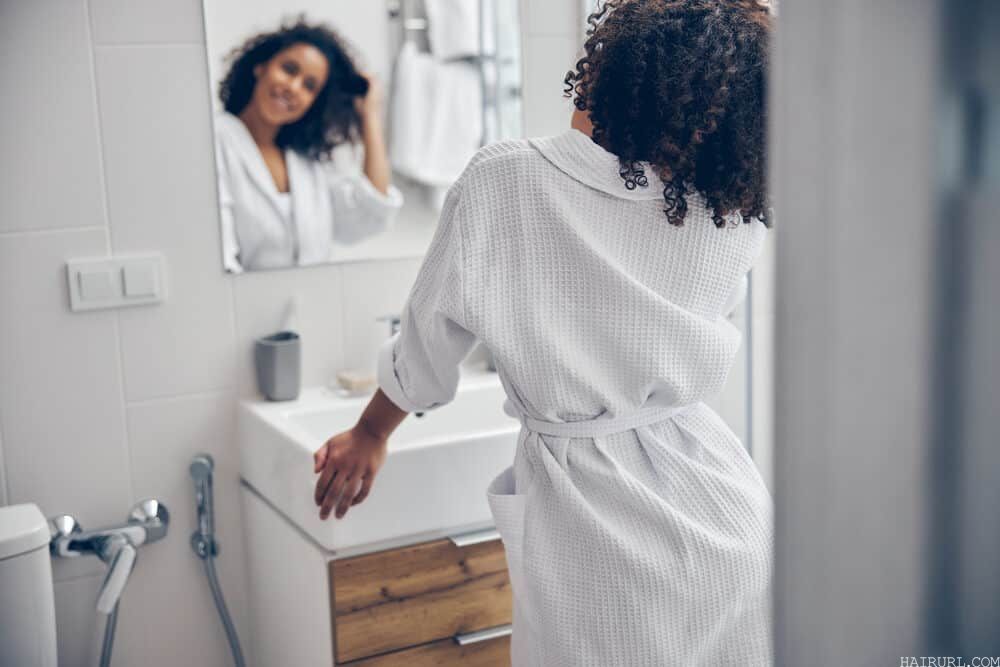 African American woman wearing a robe in the bathroom after towel drying hair