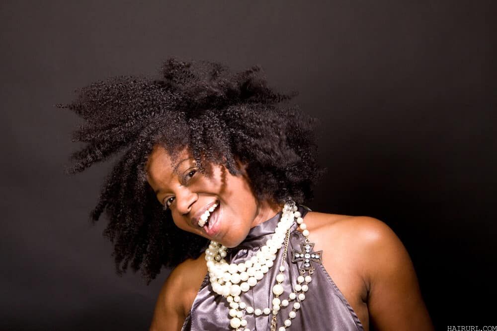 Black lady with kinky hair knots laughing as she flips from side-to-side