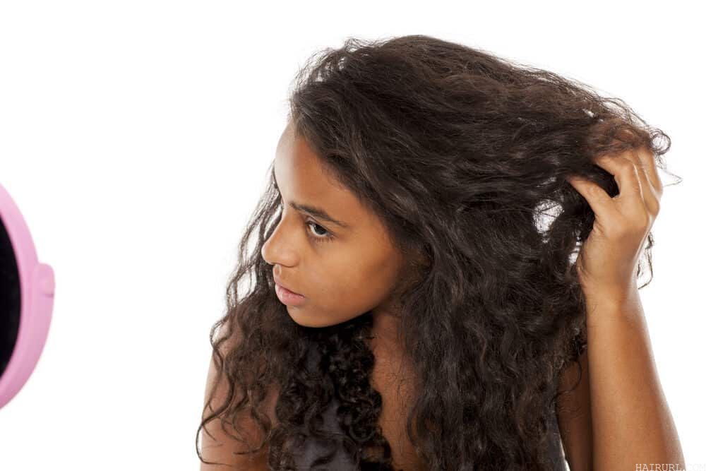 Cute black woman with a brown natural hair color connecting the last i-tip hair extension to her own hair